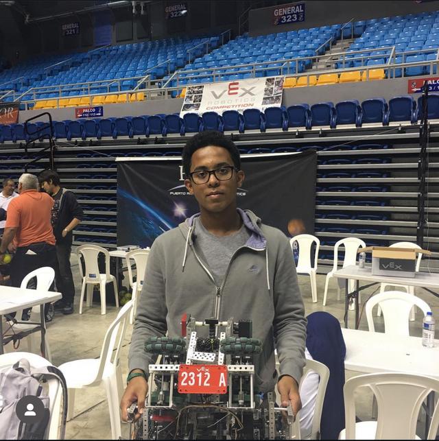 Julius at a VEX robotics competition holding his robot